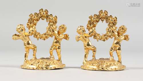 A SMALL PAIR OF GILT CHERUB MENU HOLDERS.