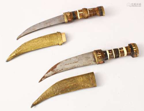 TWO EARLY SYRIAN / EASTERN HORN HANDLE DAGGERS, with gilded sheaths and decorated blades, 27cm