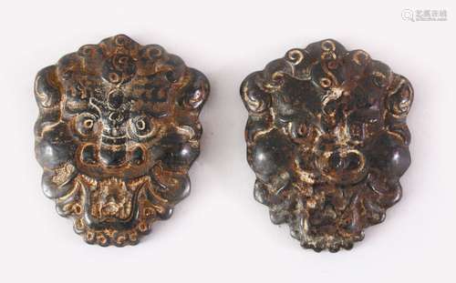 TWO TIBETAN CARVED HARDSTONE PENDANTS OF MYTHICAL MASKS, 8cm high.