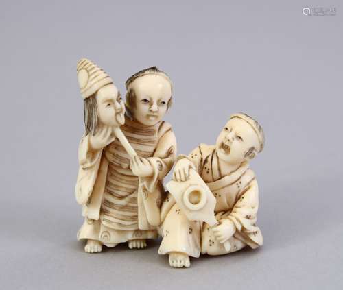 A JAPANESE MEIJI PERIOD CARVED IVORY OKIMONO OF TWO BOYS, one holding a mask, the other a small bat,