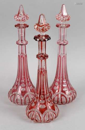 Three 19th century cranberry and clear glass decanters each of slender tapering form,