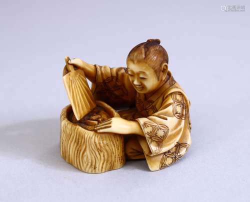 A JAPANESE MEIJI PERIOD CARVED IVORY OKIMONO - the figure seated above his hibachi waving his fan,