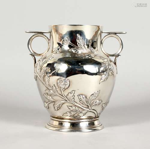 A SILVER BALUSTER SHAPED TWIN-HANDLED VASE, the body embossed with buds and leaves, on a circular