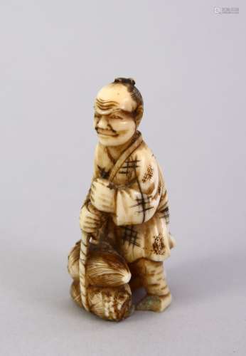 A SMALL JAPANESE MEIJI PERIOD CARVED IVORY NETSUKE - the figure carved holding tied sacks of
