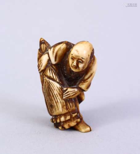 A JAPANESE MEIJI PERIOD CARVED IVORY NETSUKE, the figure holding a tied parcel, signed to side, 3.