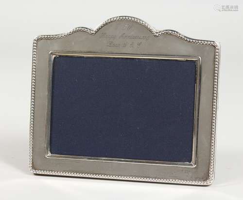 A SILVER PHOTOGRAPH FRAME, with serpentine top. 5.25ins x 6ins.