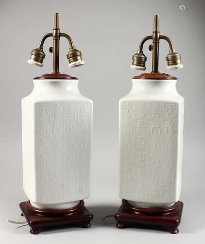 A PAIR OF WHITE PORCELAIN AND HARDWOOD CHINESE TABLE LAMPS, with moulded calligraphy design, and