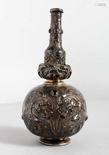 AN ART NOUVEAU BOTTLE VASE, repousse with flowers and set with red cabochon stones. 7ins high.