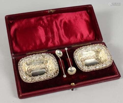 A SET OF FOUR EMBOSSED SILVER SALTS, with two spoons, boxed.