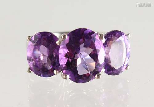 A SILVER THREE STONE AMETHYST RING.