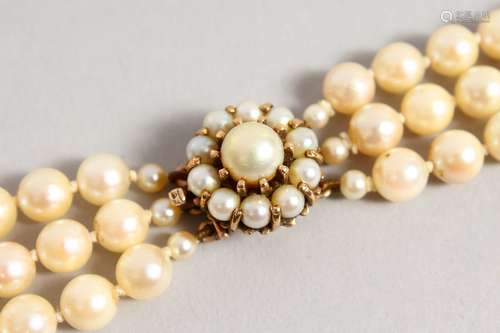 A TRIPLE ROW OF PEARLS, with 9ct gold and pearl cluster clasp.