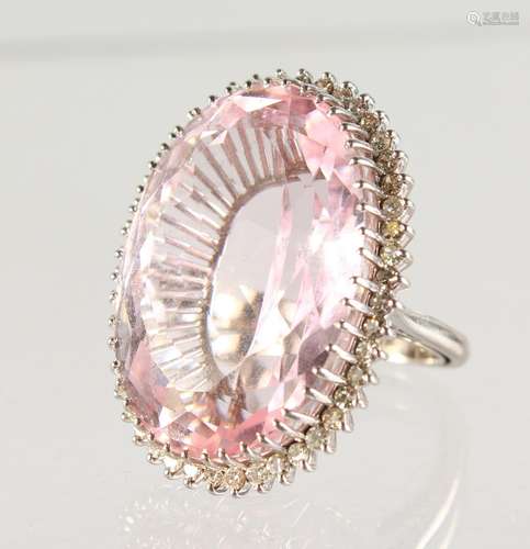 A VERY LARGE PINK OVAL STONE, surrounded by diamonds, set in white gold.