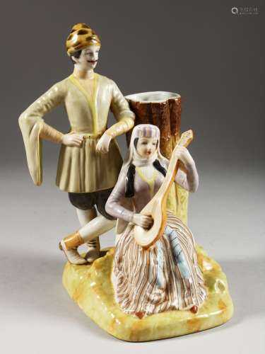 A RUSSIAN STYLE PORCELAIN VASE GROUP of a man standing and a lady playing a guitar. 10ins high.