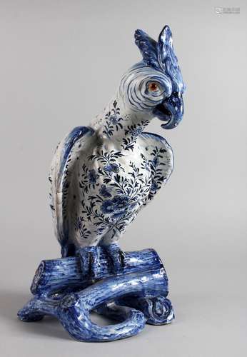 A LARGE POTTERY FIGURE OF A PARROT ON A TREE STUMP, with blue floral painted body. 16ins high.