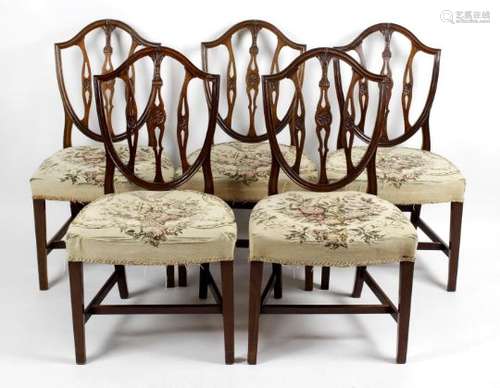 A set of five mahogany framed dining room chairs each with an open carved shield shaped back above