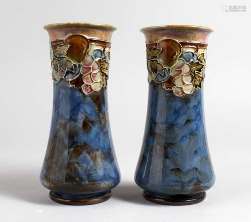 A PAIR OF ROYAL DOULTON POTTERY VASES, blue glazed with moulded fruit and vine decoration. 8ins