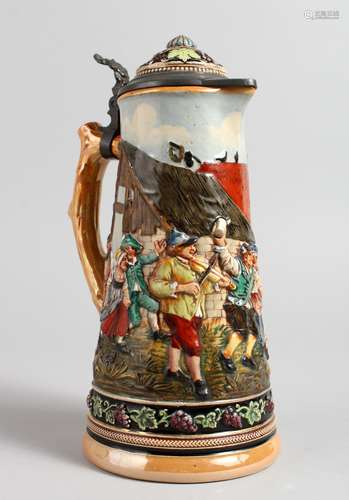 A GERMAN POTTERY LIDDED JUG, decorated with merrymaking figures. 10ins high.