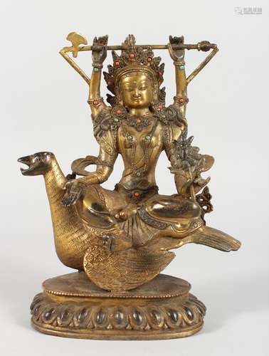 A CHINESE GILT BRONZE FIGURE OF A DEITY SEATED ON A BIRD, inset with semi-precious stones. 9.5ins