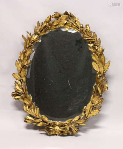 AN 18TH / 19TH CENTURY GILT FRAMED OVAL MIRROR, with well carved leaf and berry frame and ribbon and