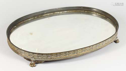 A BRASS FRAMED MIRRORED PLATEAU, of oval shape, with an ornate cast frame on paw feet, (one foot