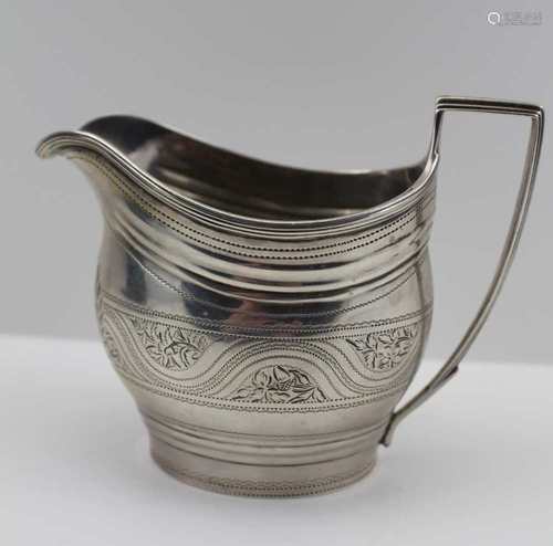 A GEORGE III SILVER MILK JUG, bright cut decoration, including a blind wreath cartouche, London