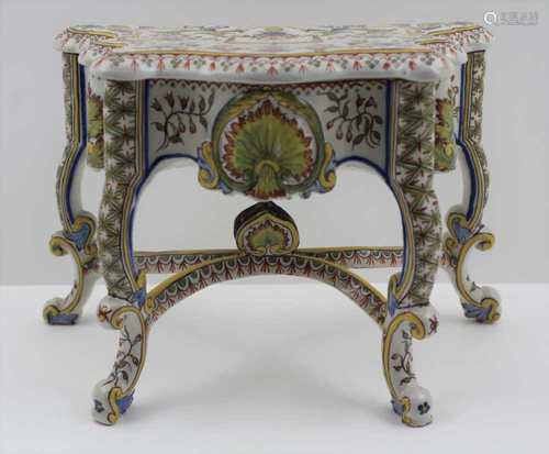 A 20TH CENTURY FAIENCE CASKET OF TABLE FORM, serpentine top with removable lid, on scroll supports