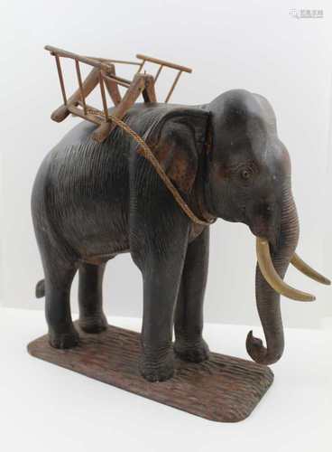 A THAI CARVED WOOD ELEPHANT, with howdah frame, the groundwork base inscribed beneath, 29.5cm