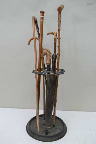 A CAST METAL STICK STAND CONTAINING A VARIED SELECTION OF WALKING STICKS and an Oriental parasol