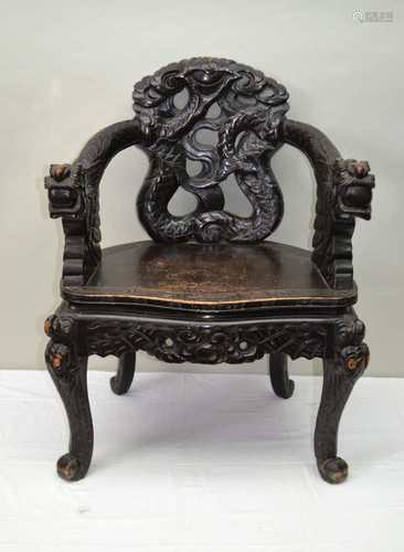 A CARVED WOOD ORIENTAL HORSESHOE BACKED CHAIR depicting twin dragons amongst the clouds, with a