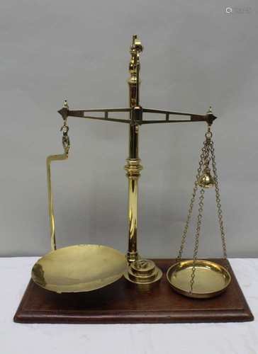 A 19TH CENTURY POLISHED BRASS SET OF BALANCE SCALES supported on a rectangular wooden plinth base,