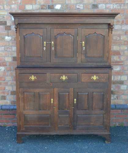 A 19TH CENTURY WELSH OAK DUODARN having shaped pediment, over three in-line panelled cupboard doors,