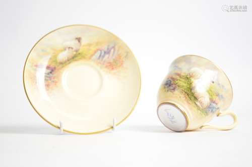 A 20th Century cup and saucer with hand painted decoration of long haired rams in moorlands,