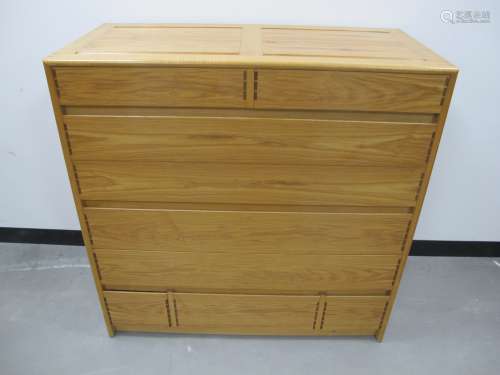 A Cotswold School style chest of drawers, oak with panelled sides and tops, mahogany drawer side,
