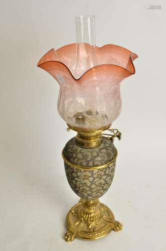 A Doulton oil lamp with cranberry glass shade, the Doulton stoneware body raised on three footed