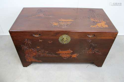 A Oriental hardwood trunk, top and front having a moulded landscape design, inset handles to