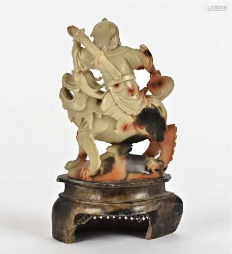 A 19th Century Chinese soapstone carved figure, modelled as a seated warrior upon a mythical