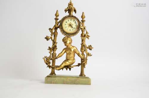 A 20th Century mantle clock with gilt putto and foliage surround, raised on an onyx stand, the