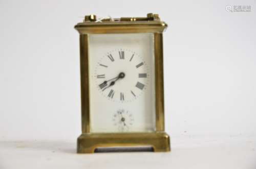 A brass carriage timepiece, the central enamel dial with Roman numerals and lower Arabic dial,