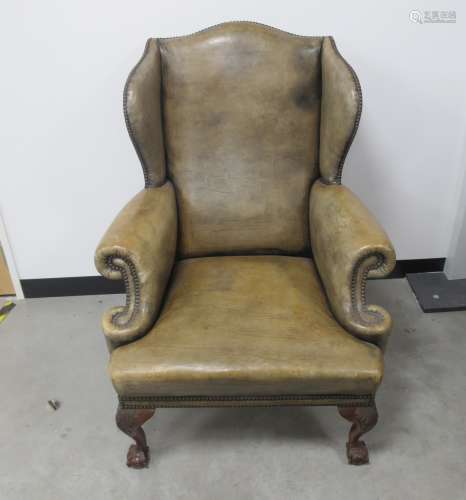 A Georgian style wing armchair , mushroom coloured leather upholstery with brass studding, raised on