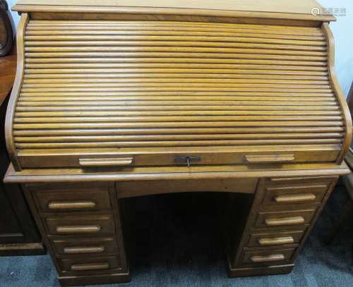 A Edwardian honey oak roll topped desk, S tambor top reviling a fitted interior, the base having