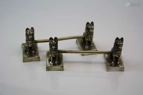 A pair of white metal knife rests with seated dog decoration c.1900.