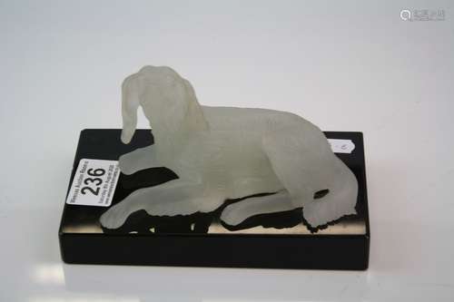 Moulded opaque glass figure of a dog on a black glass stand.