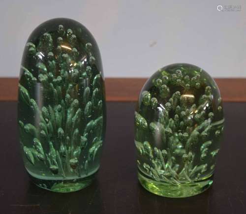 Two green glass paperweights, the largest 13cm high