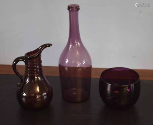 Group of three purple coloured glass wares comprising a bowl and a ewer and further glass bottle,