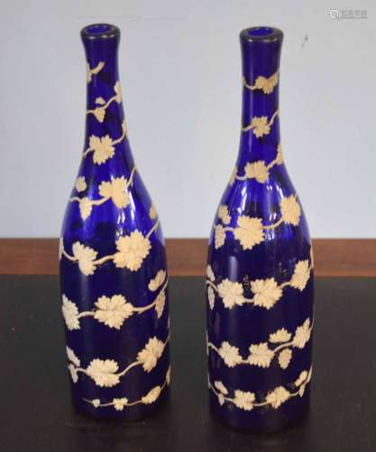 Pair of blue glass bottles overlaid with a leaf design in white and gilt, 32cm high (2)