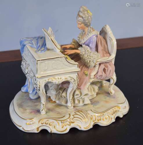 Large Continental porcelain group of a lady seated playing the piano on scroll base
