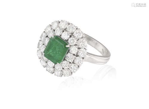 AN EMERALD AND DIAMOND CLUSTER RING, the rectangular cut-cornered emerald weighing approximately 1.