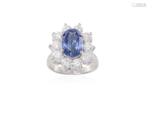 A SAPPHIRE AND DIAMOND CLUSTER RING, the oval-shaped sapphire weighing 4.11cts within a four-claw