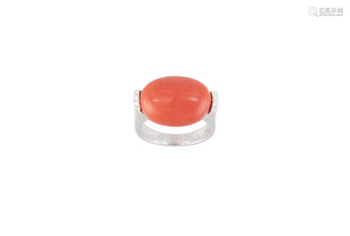 A CORAL AND DIAMOND RING, the oval-shaped cabochon coral set between brilliant-cut diamond
