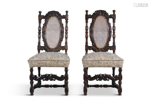 A PAIR OF WALNUT STAINED AND CARVED FRAME SIDE CHAIRS, with oval cane panel backs, the crests with